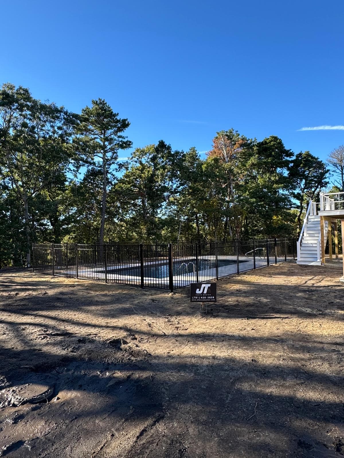 Black aluminum pool fence with JT Fence yard sign visible