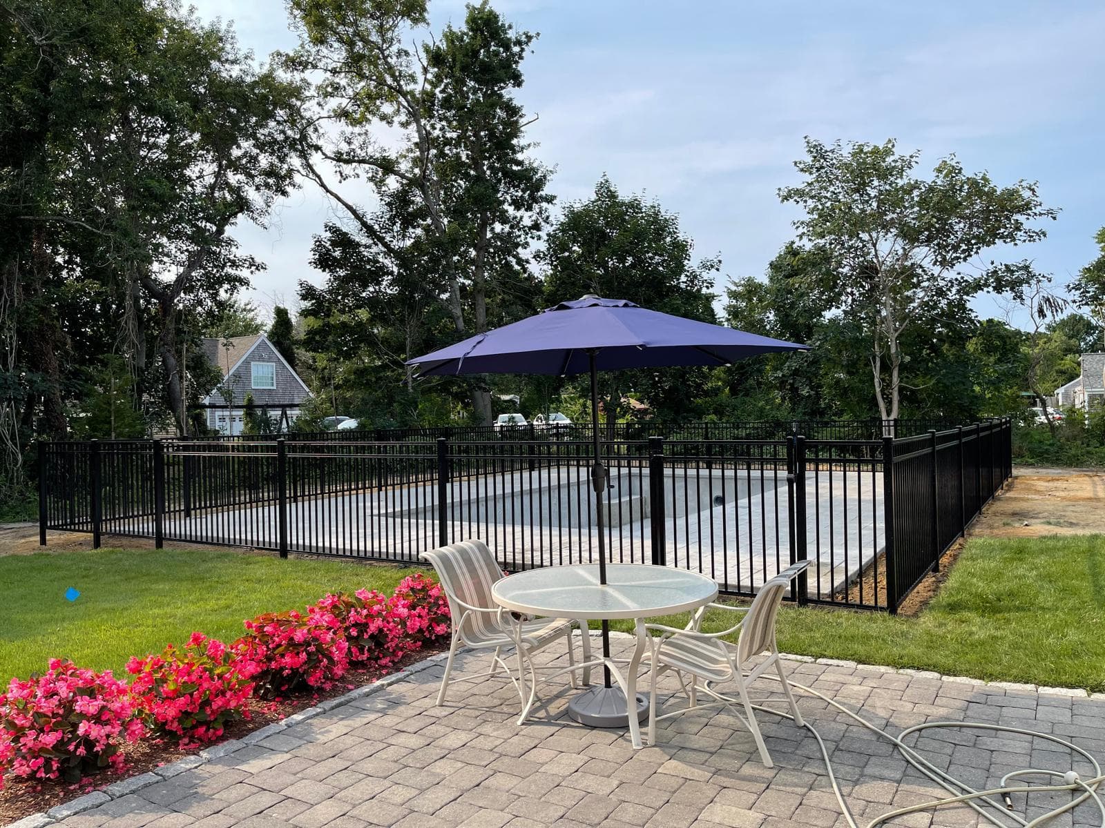 Black aluminum pool fence with patio furniture and umbrella