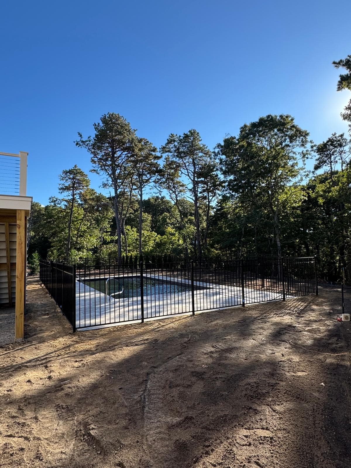 Black aluminum pool fence in wooded new construction setting