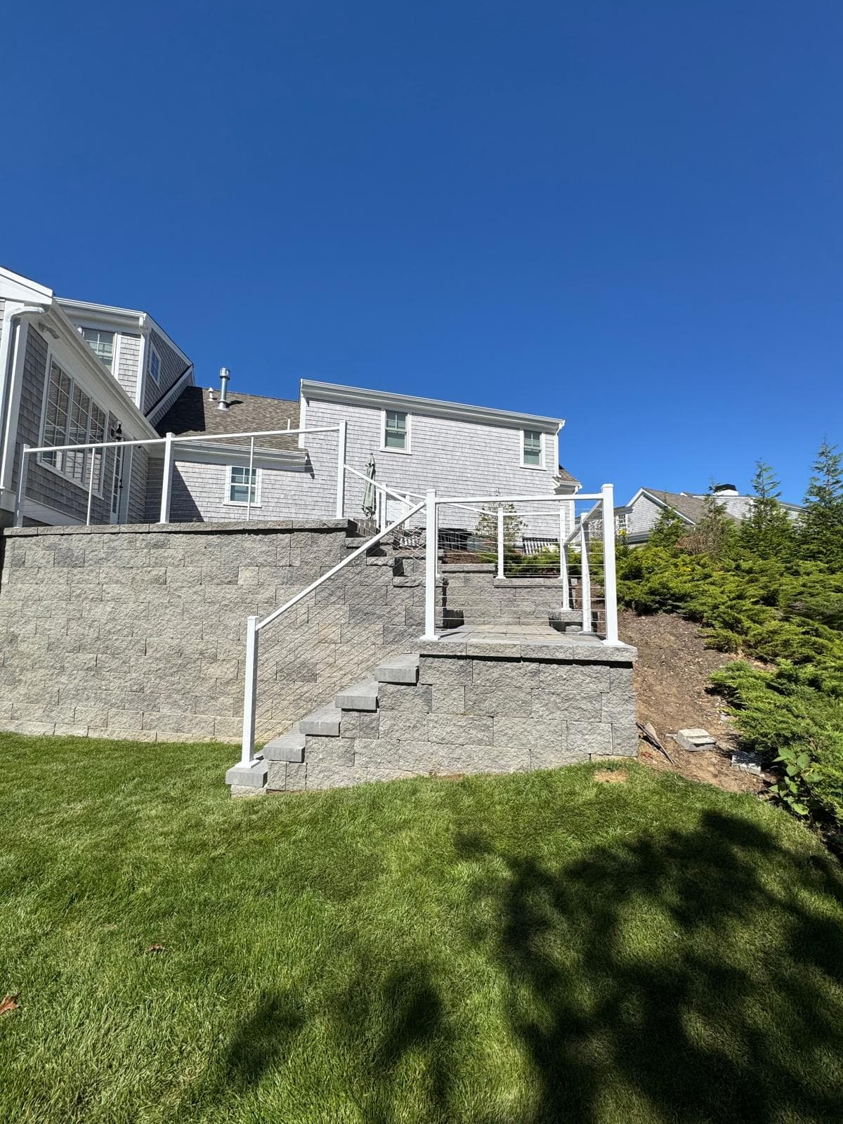 White aluminum cable railing along stone staircase — modern minimalist lines