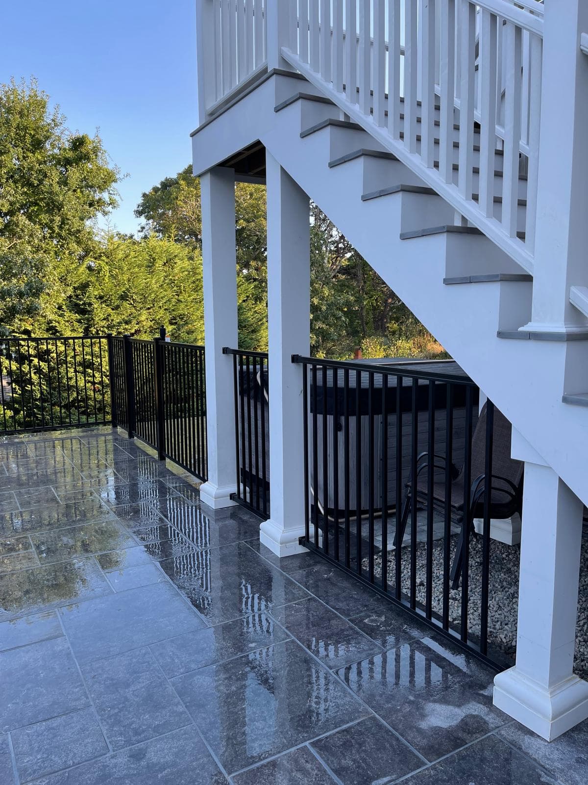 Black aluminum railing under white deck and stairs — precision installation