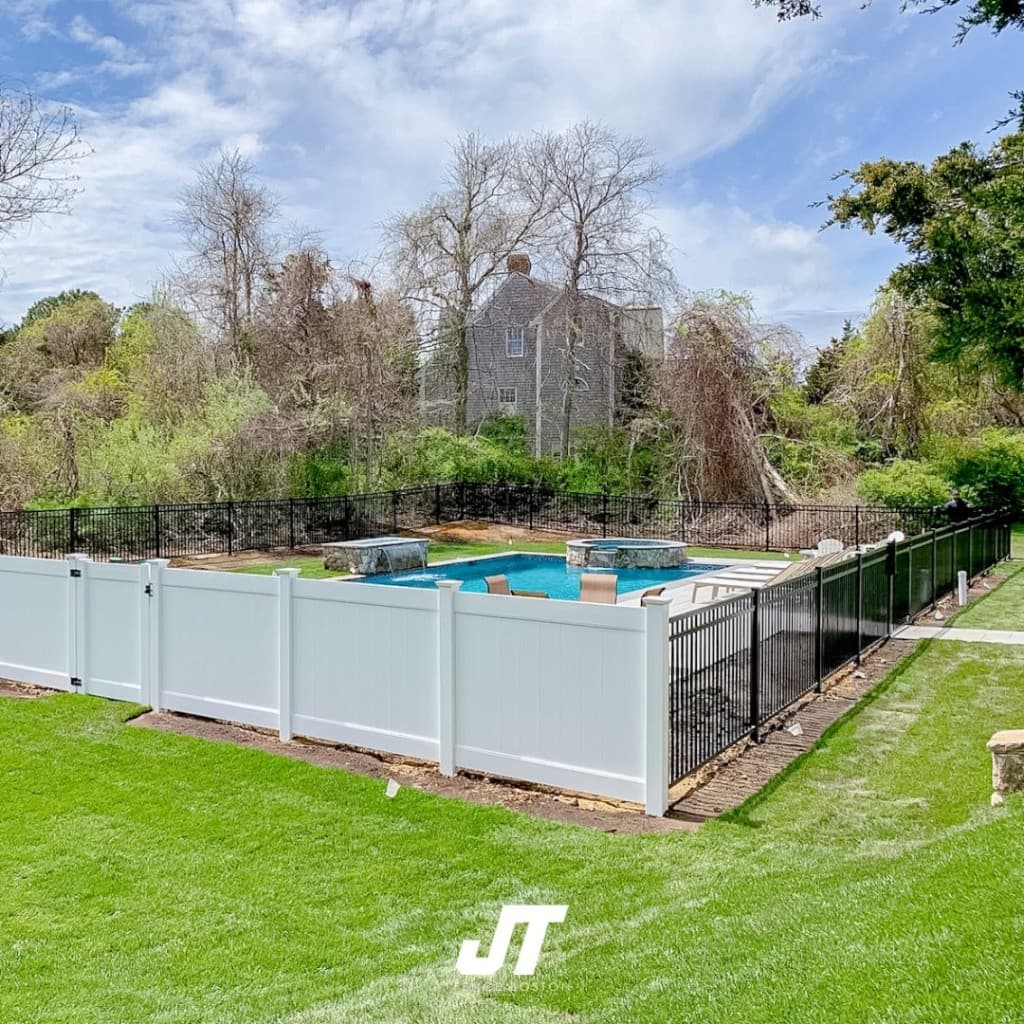 In-ground pool and spa with white vinyl privacy fence and black ornamental metal pool barrier on a Massachusetts residential property — JT Fence Inc.