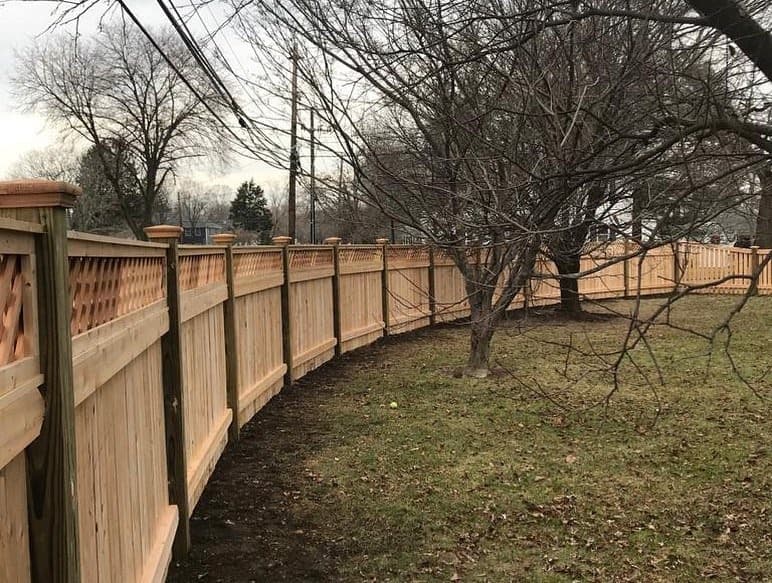 Wood fence with decorative top detail or lattice-style finish for airflow and curb appeal