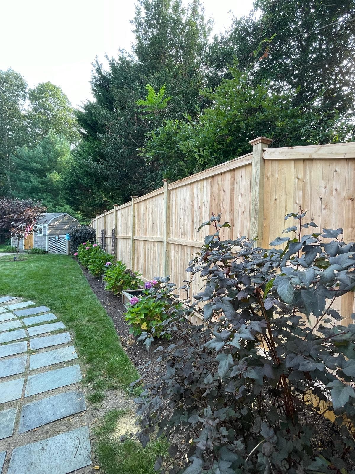 Natural cedar/wood privacy fence along landscaped residential yard